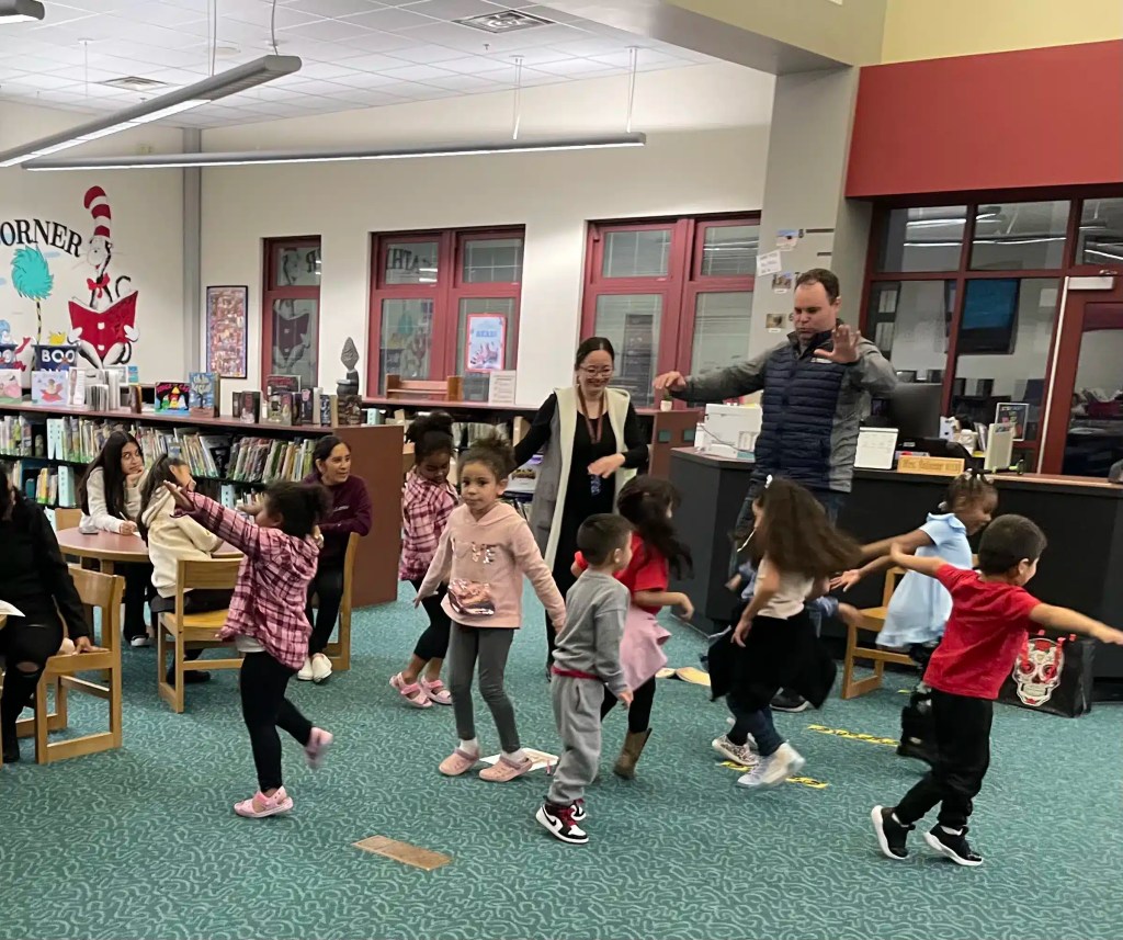 Students engaging in movement-based learning during a bilingual literacy activity in a school library